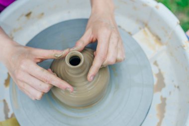 Çömlekçi çarkında çalışan kadınlar. Eller bardaktan bir kupa yontuyor.