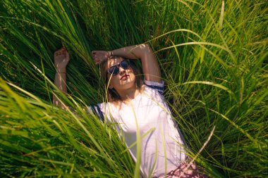 Tişört tasarım konsepti. Güzel bir kız çimenlerde beyaz tişörtle yatıyor.
