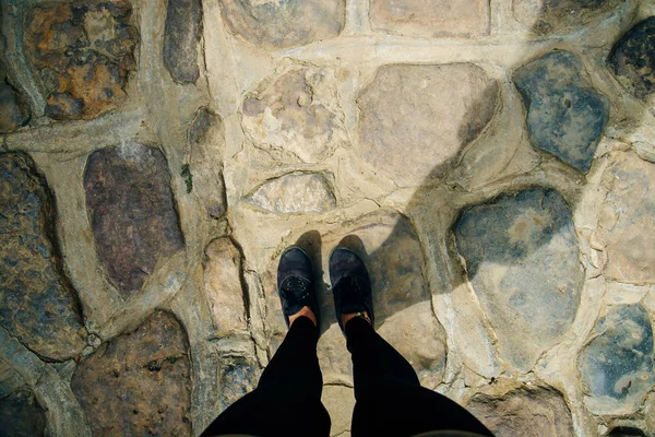 Två fötter i skor stående på sten trottoaren. Direkt ovanför vyn. — Stockfoto