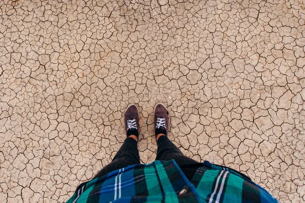 Torr mark är täckt med små sprickor som ett begrepp för torka och global uppvärmning. ovanifrån på benen i sneakers — Stockfoto