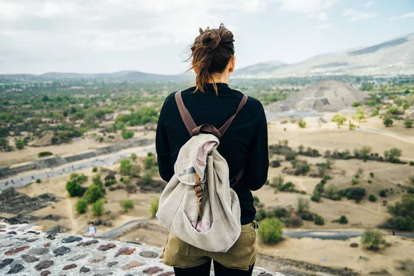 Teotihuacan, Meksika. Sırt çantası ve şapkalı Meksikalı Amerikalı bir turist, Piramidin tepesinden manzaranın keyfini çıkarır. Güneş