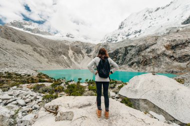 Laguna 69, Peru. Bir kız ile bir sarı ceket kot pantolon mavi göle karşı onu geri duruyor