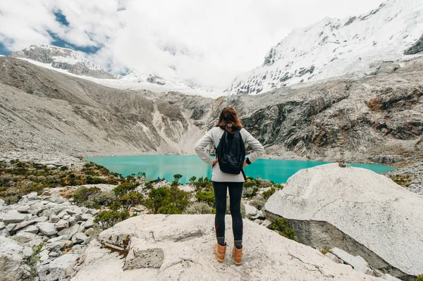 拉古纳 69, 秘鲁。一个女孩站在她的背部对蓝色的湖穿着黄色夹克牛仔裤 — 图库照片