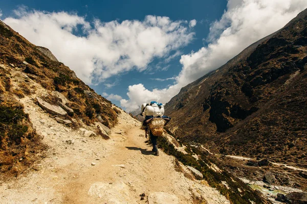 Porter and Sherpa walking with big bag baggage luggage in Himalaya Mountains in Nepal. — Stock Photo, Image