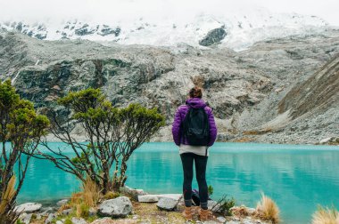 Laguna 69, Peru. Bir kız ile bir sarı ceket kot pantolon mavi göle karşı onu geri duruyor