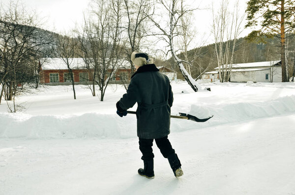 Janitor cleans snow shovel after a snowfall