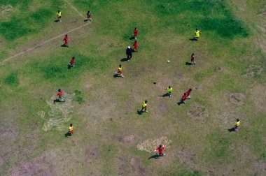 Oyuncular bir futbol maçı oynuyorlar. Yükseklikten gelen bir dronla havadan çekim yapıyorlar.