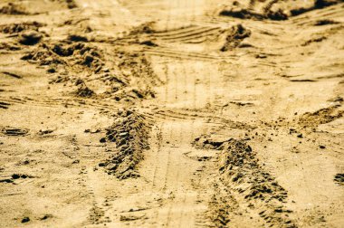 Sarı kumdaki büyük bir kamyonun lastik izleri..