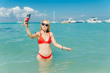 Kırmızı mayolu güzel sarışın Playa Norte, Isla Mujeres plajında selfie çekiyor. Meksika.