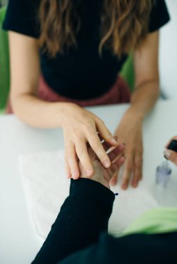 Manikürcü, bir kaplıcadaki veya güzellik salonundaki bir bayanın tırnaklarına oje sürüp ellerini kapatıyordu..