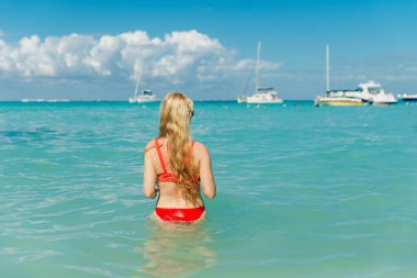 Plajda, Playa Norte, Isla Mujeres 'de kırmızı mayo giymiş güzel bir sarışın. Meksika.