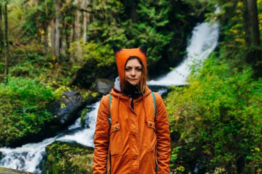 Sonbaharda şelalenin arka planındaki kız, Kanada.