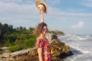 Şapkalı ve siyah elbiseli güzel bir kız okyanusa bakıyor. TULUM, Meksika.