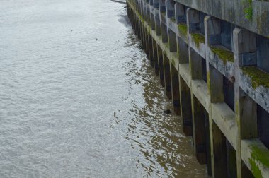 Çamurlu Thames nehri ile rıhtımların eski temellerinin görüntüsü