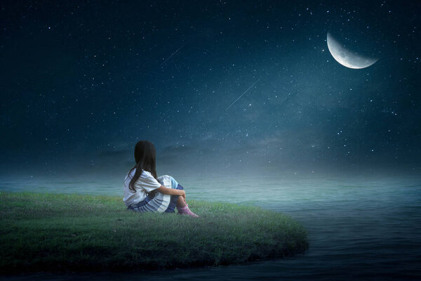 The little girl sat happily looking at the moon in winter.