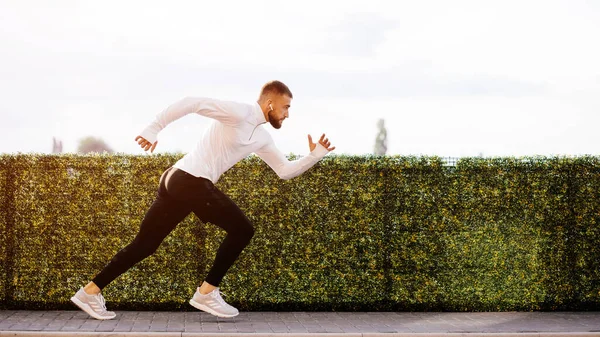 Sporcu adam koşmaya başladı. Genç adam koşuyor. Endüstriyel kentte hızlı koşan bir koşucu. Spor, atletizm, fitness, koşu aktivitesi. Egzersiz, yaşam tarzı konsepti. Başlangıç için koşucu..