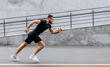Sporcu adam koşmaya başladı. Genç adam koşuyor. Endüstriyel kentte hızlı koşan bir koşucu. Spor, atletizm, fitness, koşu aktivitesi. Egzersiz, yaşam tarzı konsepti. Başlangıç için koşucu..