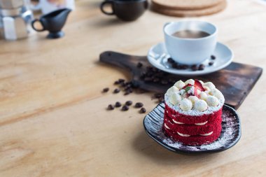 Tayland keki. Kadife kırmızı pasta. Kurabiyeler ahşap masada kırmızı pasta ve arka planda sıcak kahve ile süslenmiş..