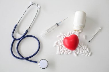Beyaz ahşap arka planda steteskop ve kırmızı kalp. İlaç ve sağlıklı..
