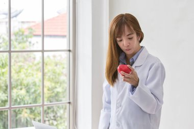 Kırmızı kalpli gülümseyen kadın doktorun portresi. Kırmızı kalpli, dost canlısı genç bir doktor. asya.