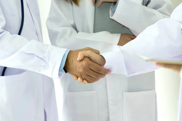 Medical and healthcare concept. Young medical people handshaking at the hospital. Team doctors working at office. Active people at clinic. Tablet on hand and stethoscope around on neck. asian people.