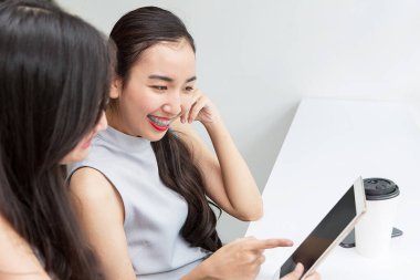 İnternetten alışveriş yaparken tabletle ödeme yapan gülümseyen genç bir kızın fotoğrafı. Asyalı kadınlar.