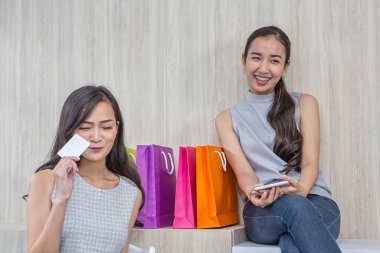 Kafede kredi kartı ve akıllı telefonla ödeme yapan mutlu bir kadın. Kadın temassız ödeme almış. İnsanlar, finans, teknoloji ve tüketici konsepti. Çevrimiçi alışverişte cep telefonuyla ödeme yapan gülümseyen genç bir kızın fotoğrafı..