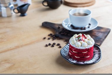 Tayland keki. Kadife kırmızı pasta. Kurabiyeler ahşap masada kırmızı pasta ve arka planda sıcak kahve ile süslenmiş..
