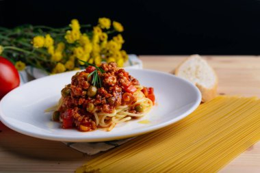 Tahta masadaki sade beyaz tabakta et soslu İtalyan spagettisi. Domatesli spagetti..