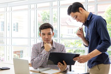 Ofiste çalışan ve tartışan iş adamları. Bilgisayar ve internet kullanan iki erkek. İş adamı odada bilgi topluyor. Proje üzerinde birlikte çalışıyoruz. Asyalılar.