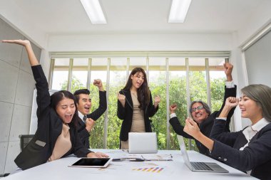 Bir grup mutlu iş adamı ofiste tezahürat yapıyor. Başarını kutla. İş ekibi ofiste iyi bir işi kutluyor. Asyalılar.