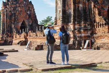 Doğu Asya yaz tatili. Beyaz adam ve Asyalı kadın turist Wat Chaiwatthanaram tapınağına bakıyorlar. Turistler sabahları Tayland 'ın Ayutthaya kentindeki tapınakta seyahat ediyorlar..