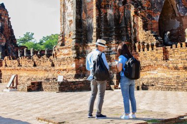 Doğu Asya yaz tatili. Beyaz adam ve Asyalı kadın turist Wat Chaiwatthanaram tapınağına bakıyorlar. Turistler sabahları Tayland 'ın Ayutthaya kentindeki tapınakta seyahat ediyorlar..