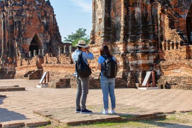 Doğu Asya yaz tatili. Beyaz adam ve Asyalı kadın turist Wat Chaiwatthanaram tapınağına bakıyorlar. Turistler sabahları Tayland 'ın Ayutthaya kentindeki tapınakta seyahat ediyorlar..