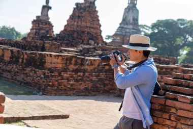 Doğu Asya yaz tatili. Kafkasyalı turist Wat Chaiwatthanaram tapınağına bakıyor. Gezginler DSLR kameralarıyla fotoğraf çeker. Tayland 'ın Ayutthaya şehrinde seyahat et. Asya turisti.
