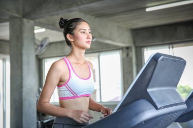 Kadınlar bir ağırlık kontrol programına giriyor. Koşu bandında koşan gençler. Spor salonunda antrenman yapan genç bir kadın. Güzel atletik kadın spor salonunda antrenman yapıyor..