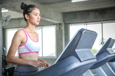 Kadınlar bir ağırlık kontrol programına giriyor. Koşu bandında koşan gençler. Spor salonunda antrenman yapan genç bir kadın. Güzel atletik kadın spor salonunda antrenman yapıyor..