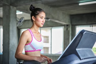 Kadınlar bir ağırlık kontrol programına giriyor. Koşu bandında koşan gençler. Spor salonunda antrenman yapan genç bir kadın. Güzel atletik kadın spor salonunda antrenman yapıyor..