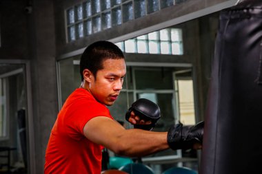 Sporcular spor salonunda yumruk atıyor. Spor salonundaki kum torbasında boks eğitimi almış bir boksörün erkek hareketi. Boksör antrenmanı spor kulübünde kum torbasıyla yapılıyor..