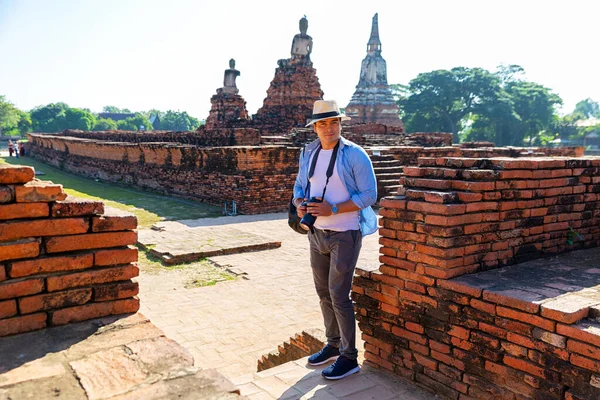 Eastern Asia summer holidays. Caucasian man tourist from back looking at Wat Chaiwatthanaram temple. Tourist travel in the morning at temple in old city of Ayutthaya in Thailand. Asia tourist.