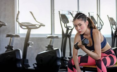 Konsept fitness spor yaşam tarzı. Kız dambılları kaldırıyor. Kas kaslarını şişiren halterli aktif sporcu kadın..
