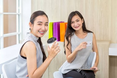 Kredi kartı ve cep telefonuyla internetten alışveriş yapan gülümseyen genç bir kızın fotoğrafı..