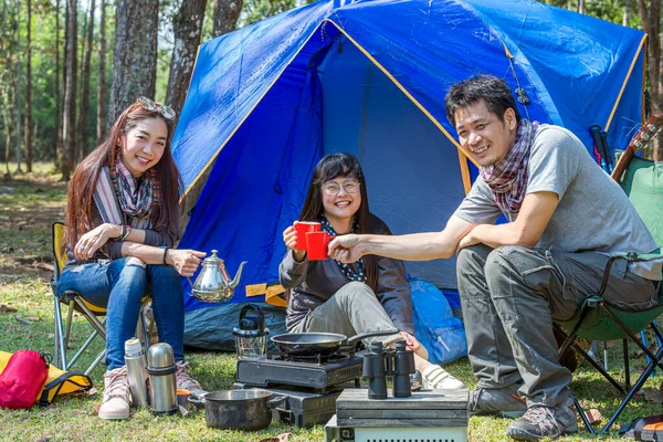 Tourists are camping in the forest. Group of adventure tourist camping enjoy and happy in coffee time with guitar playing together of summer.