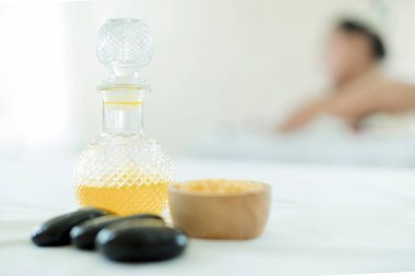 Doğal kozmetik ve konsept. Tuzu masaj yağı ve banyo havlusuyla kaplayın. Bir şişe masaj yağı, sıcak taş kaplıca ve tuz ile güzellik merkezinde masaj yapan bir kadının arka planı..