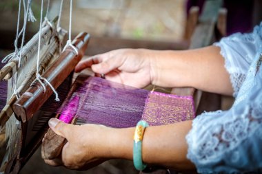 Geleneksel Isan Tayland ipeği dokuması. Yaşlı kadın elle dokuma tezgahında geleneksel bir şekilde ipek dokuyor. Tayland. Seçici odak.