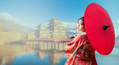 Asyalı kadın turistler. Kırmızı şemsiye tutan bir kimono giyen Japon kız. Japonya 'nın Nagano bölgesinin ünlü turistik yerlerinde geleneksel Japon kimonosu giyen güzel bir kadın. Mesaj için yer var. Kopyalamak için boşluk.