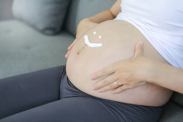 pregnant and write icon happy. Pregnant woman with cream write face happy on the belly.