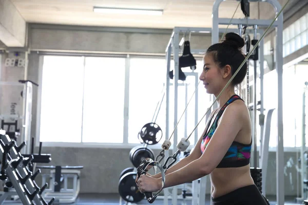 Young people exercising in the gym. asian body builder working out in gym using fitness straps in the gym center.