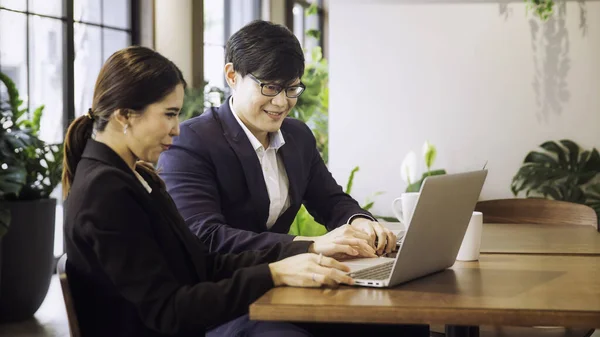 Co working space concept. Asian business looking in front of laptop while sitting at co-working space. young women and man working of new ideas in coffee shop.