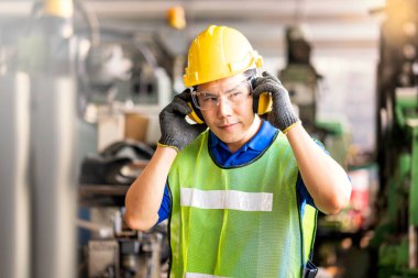 Professional technicians wear protective equipment and hard hats in large industrial plants. Protective and Safety Equipment eye wear, ear plug, vis clothes and protective helmet. clipart